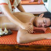 Asian man in beach spa salon getting oil massage near beach and looking happy in Thailand. Spa, resort, beauty and health concept.