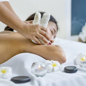 portrait of young beautiful woman in spa environment, massage with spa herbal balls