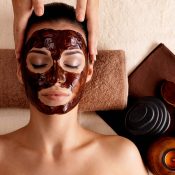 Spa massage for young woman with facial mask on face - indoors